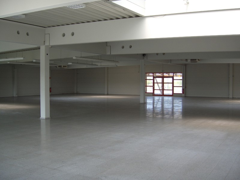 Leere, lichtdurchflutete Industriehalle mit glattem Boden.