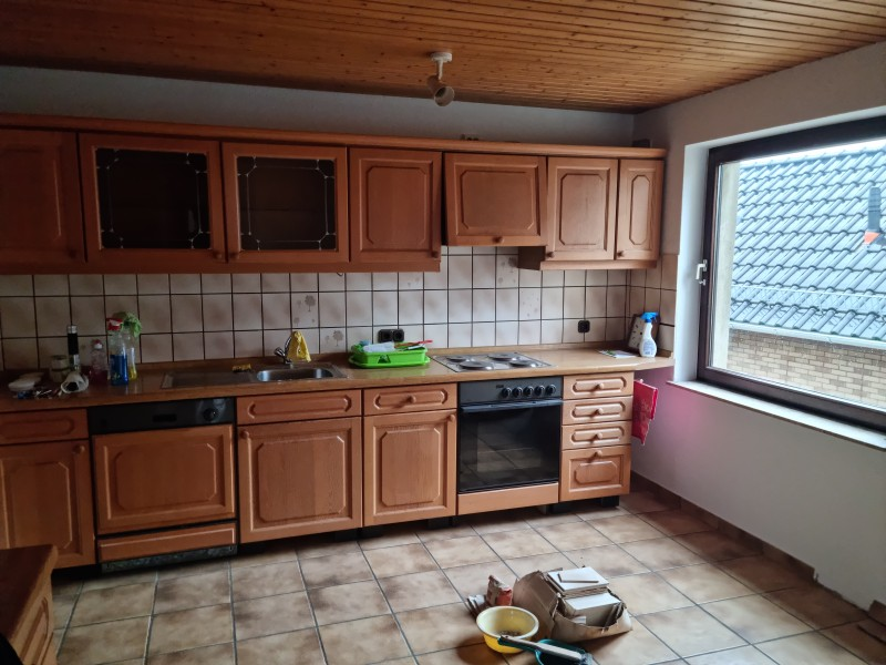 Küche mit rustikalen Einbauschränken, Fliesenspiegel und großem Fenster.