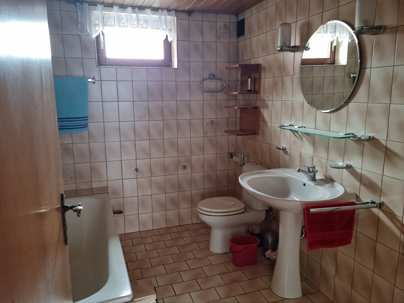 Retro-Bad mit Badewanne, Fenster und beiger Fliesenverkleidung.