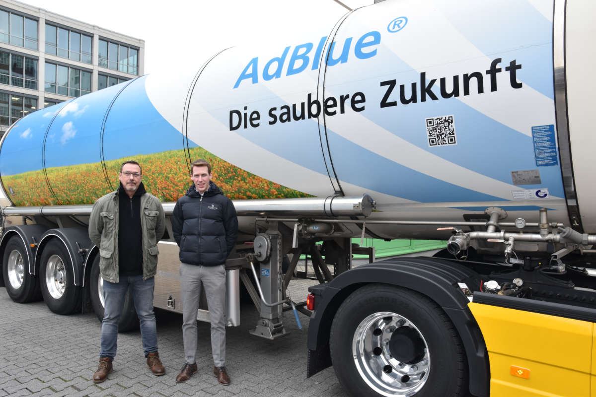 Zwei Mitarbeiter stehen vor einem AdBlue®-Tanklastzug mit der Aufschrift „Die saubere Zukunft“.