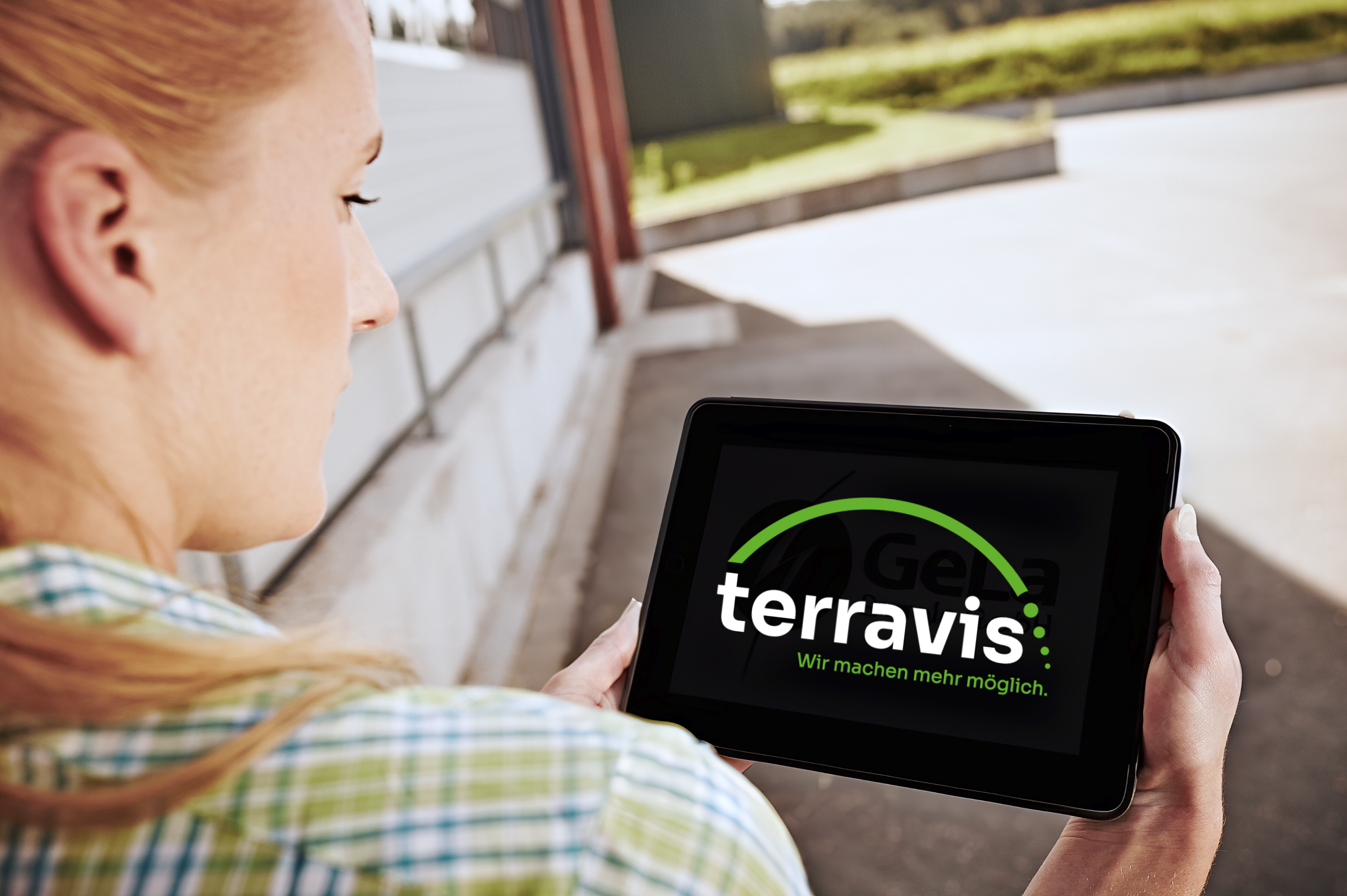 Eine Frau hält ein Tablet. Auf dem Tablet ist das TerraVis Logo zu sehen.