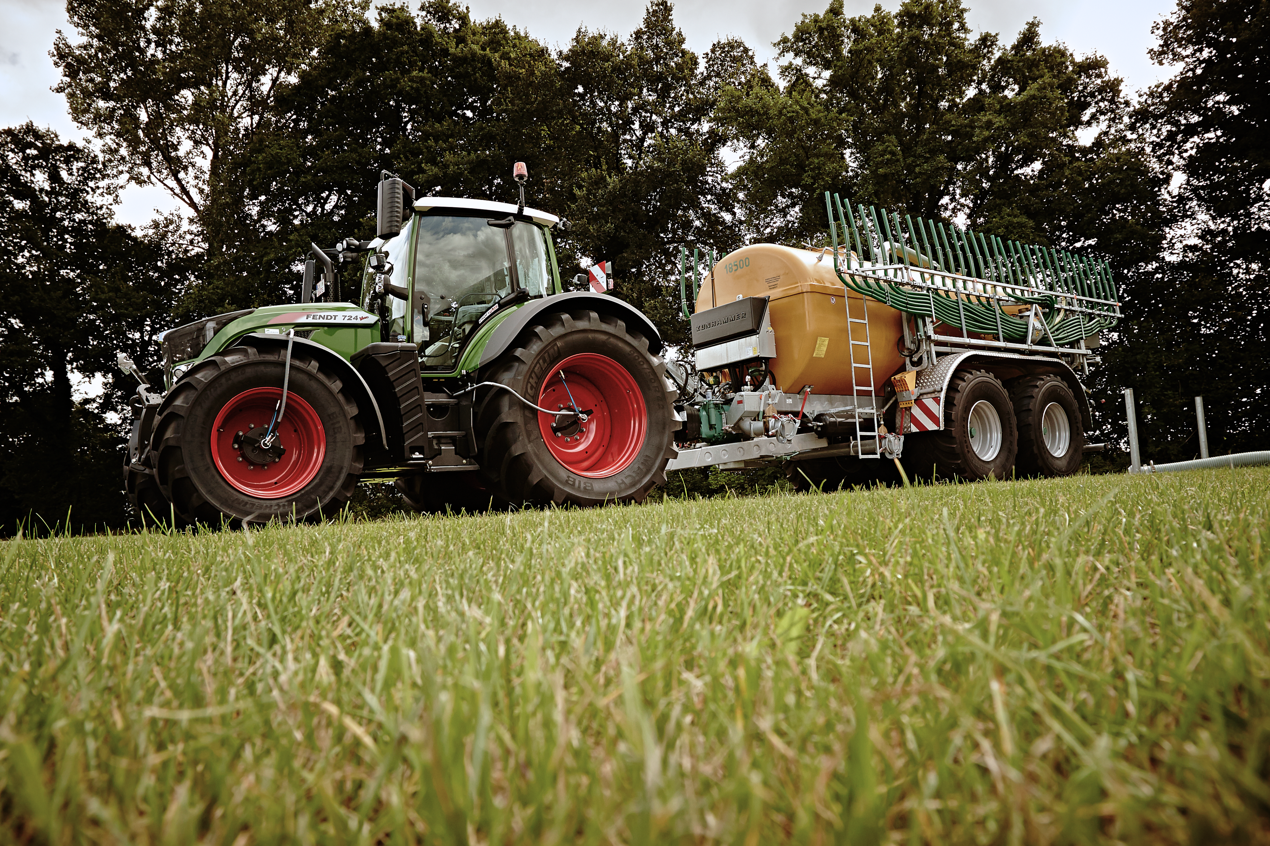 Ein Traktor mit Güllefass vor einer Grünfläche.