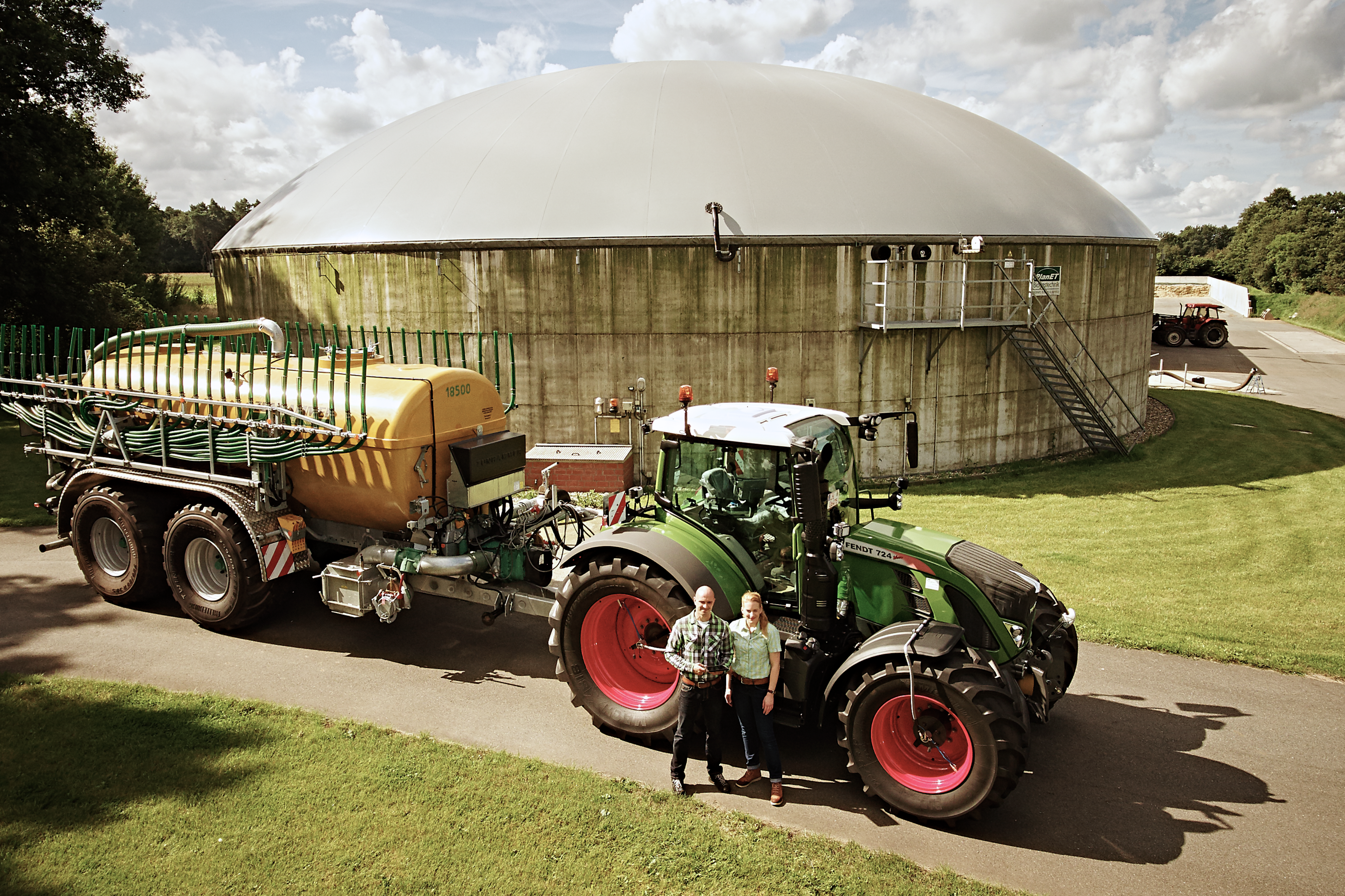 Ein Traktor steht vor einer Biogasanlage. Das Bild ist von oben aufgenommen.