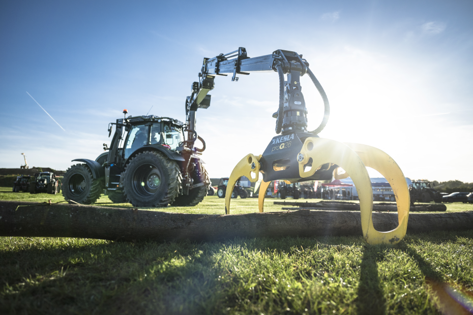 Valtra-Traktor mit Kesla-Holzgreifer bei Forstvorführung im Sonnenlicht