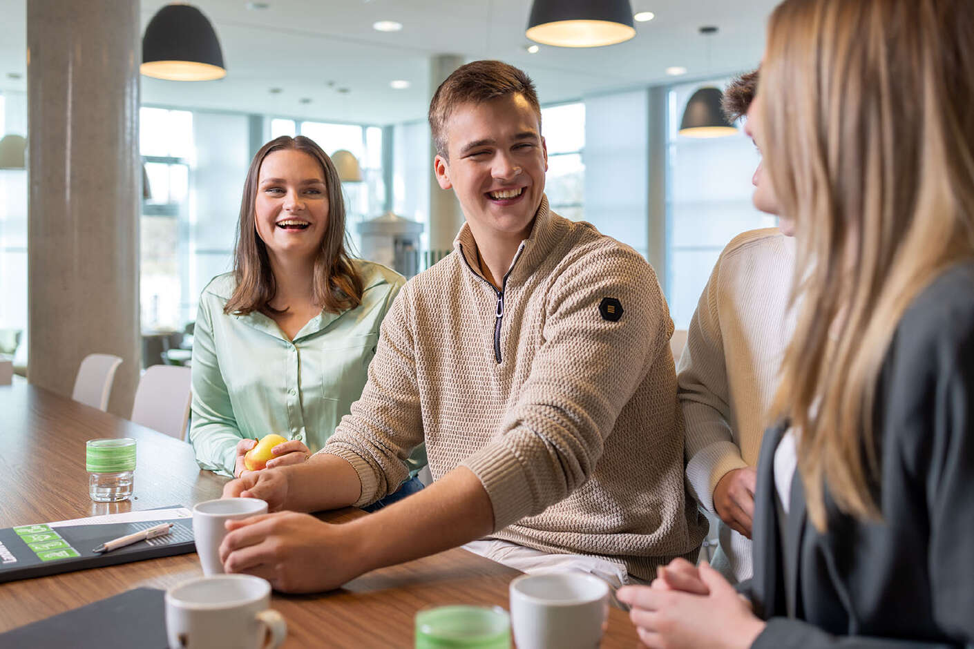 Zwei junge Frauen und ein junger Mann unterhalten sich und lächeln