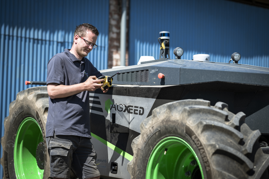 Landwirt steht neben Agbot von Agxeed und nimmt Einstellungen vor