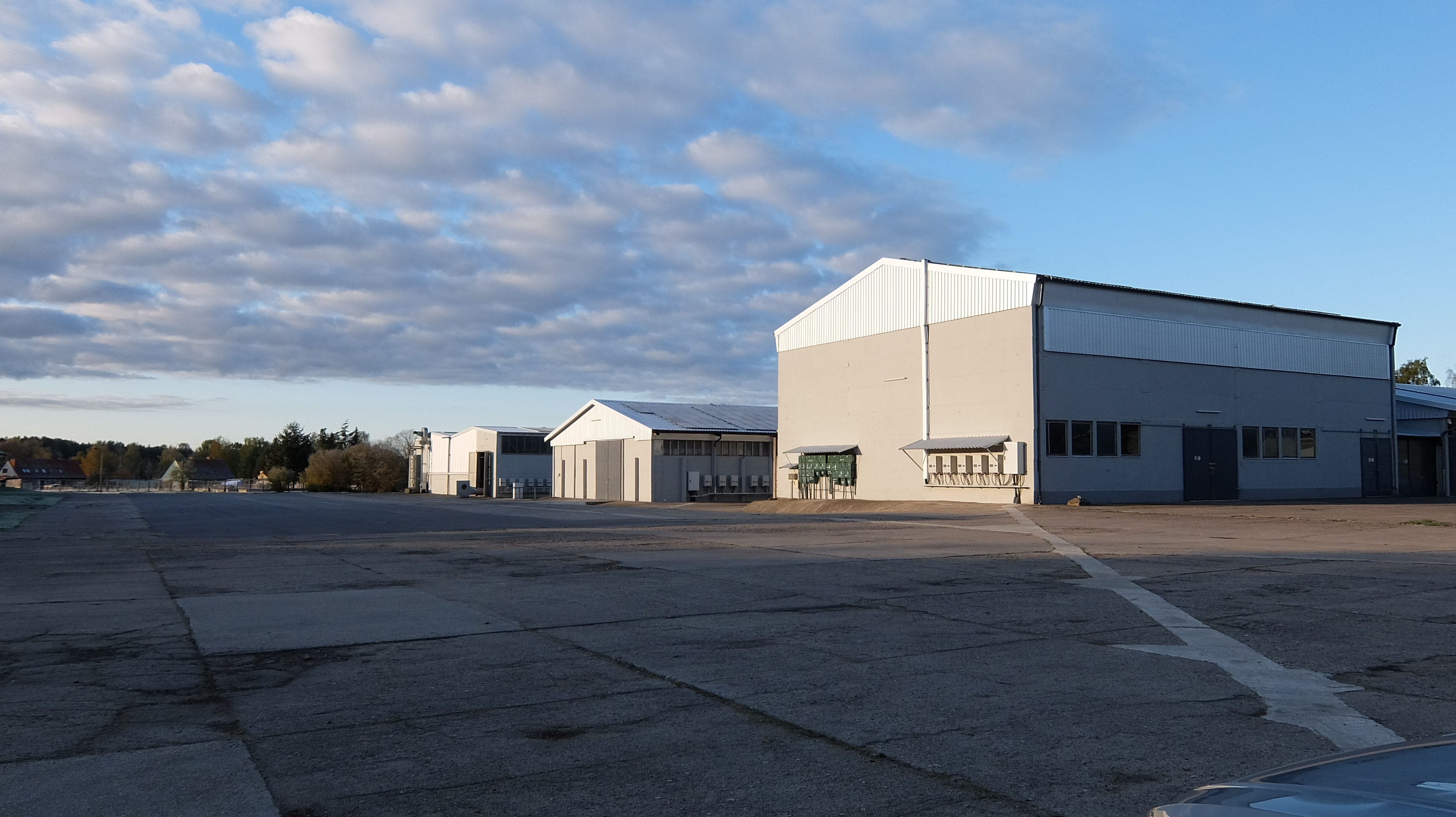 Große Industriehalle mit grauer Fassade und weitläufiger Asphaltfläche.