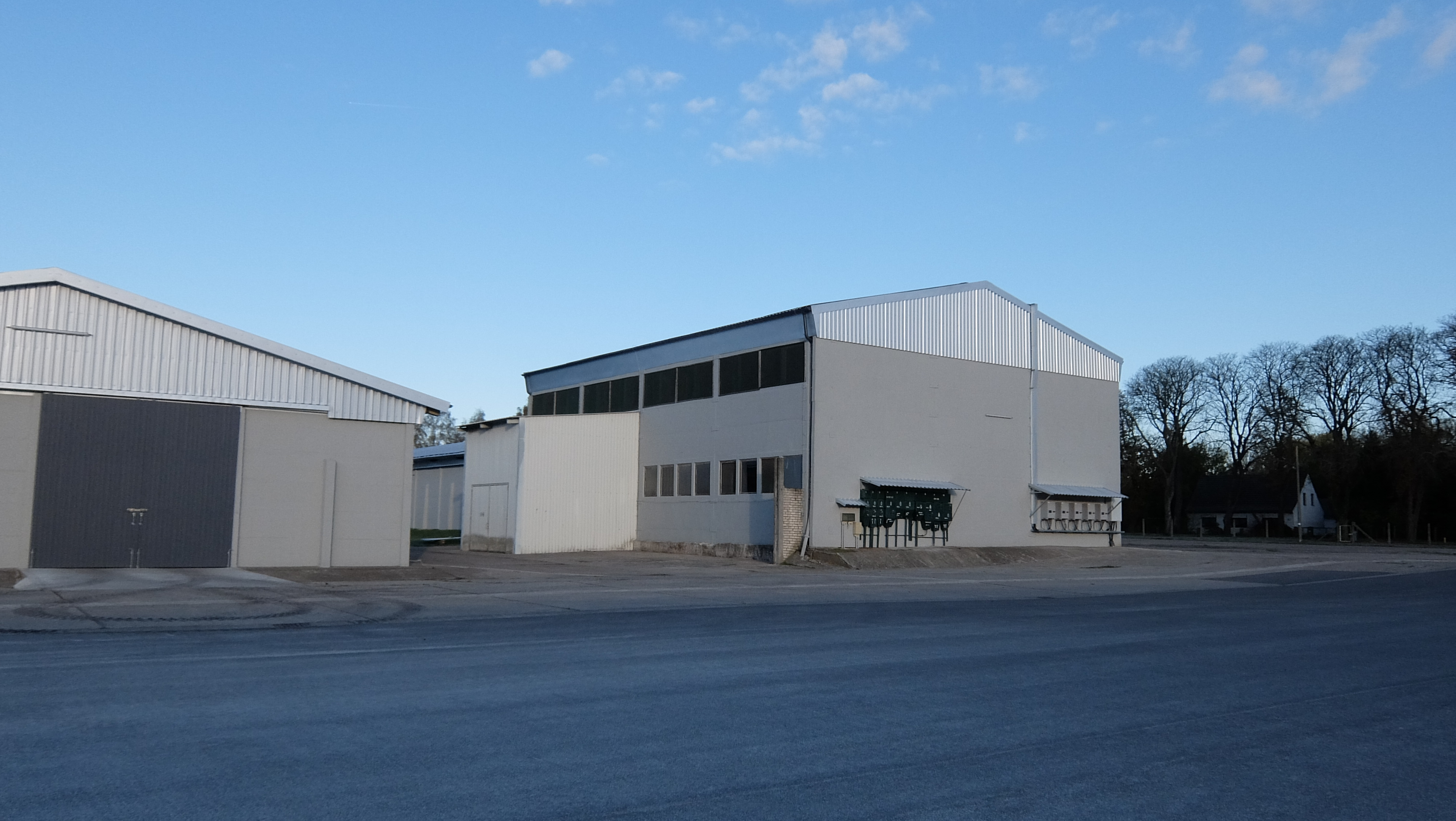 Große Industriehalle mit weißer Fassade und breiter Zufahrtsfläche.