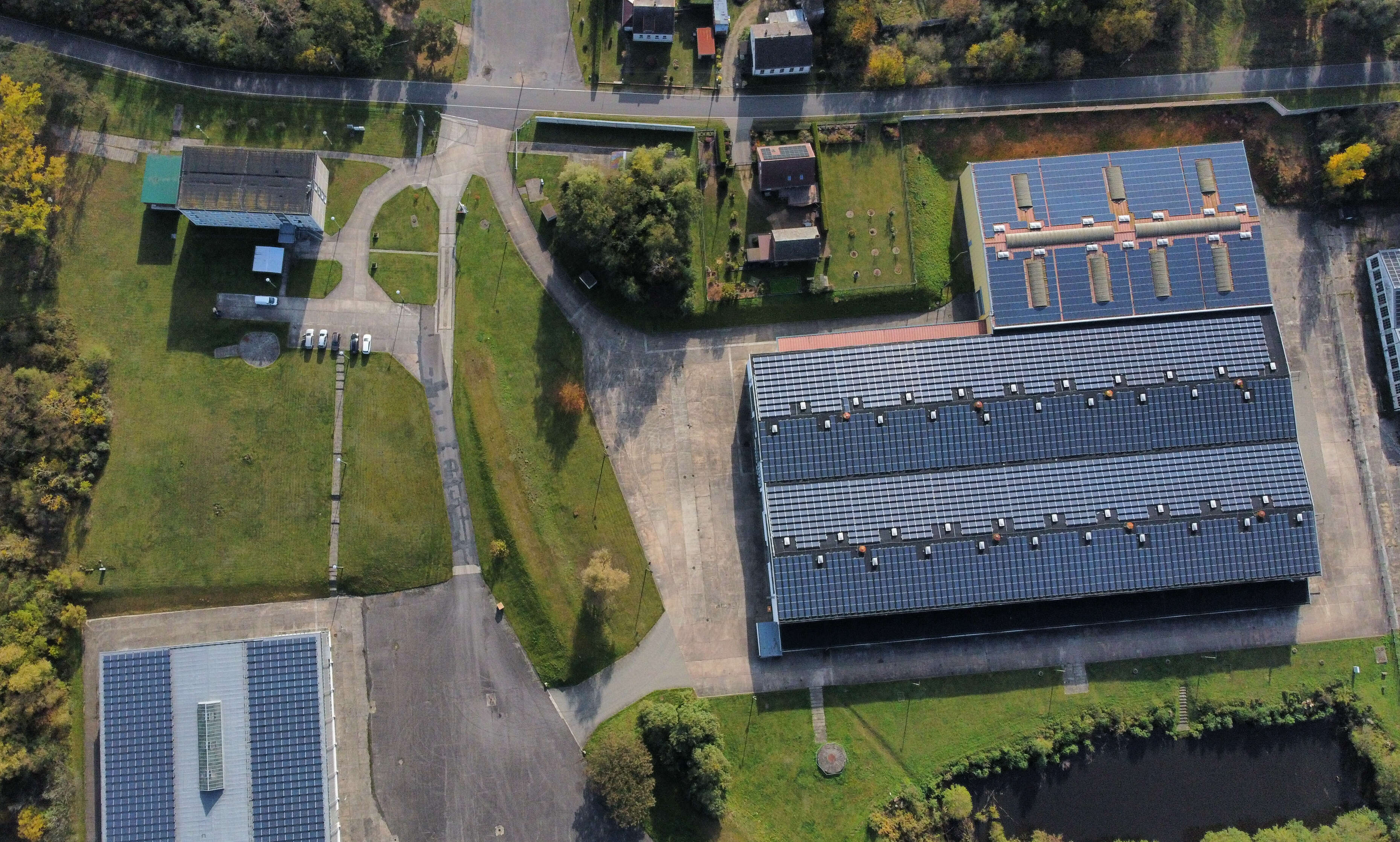 Luftaufnahme mit Industriehalle, Zufahrtsstraßen und umliegender Grünfläche.