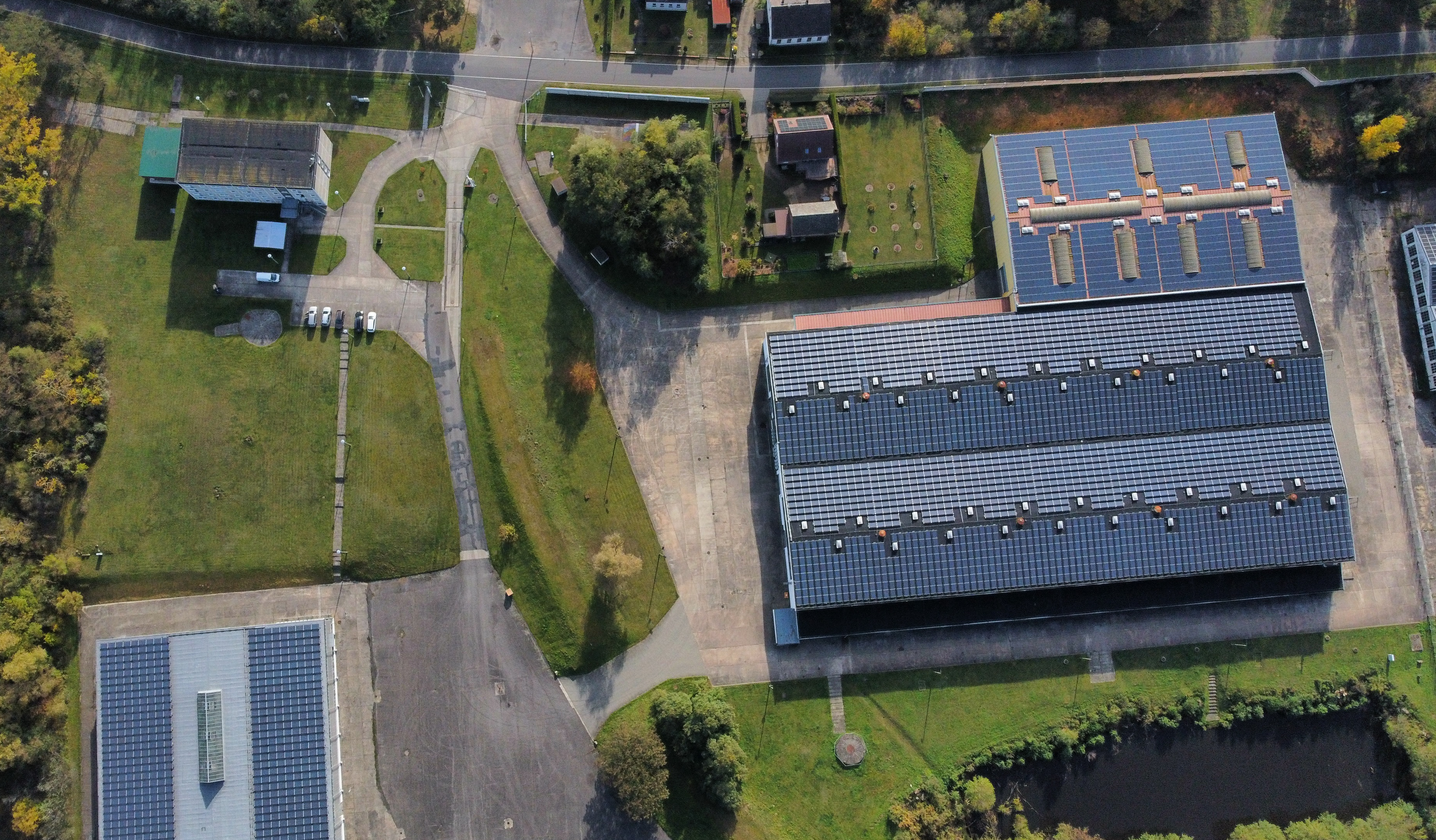 Luftaufnahme mit Industriehalle, Zufahrtsstraßen und umliegender Grünfläche.