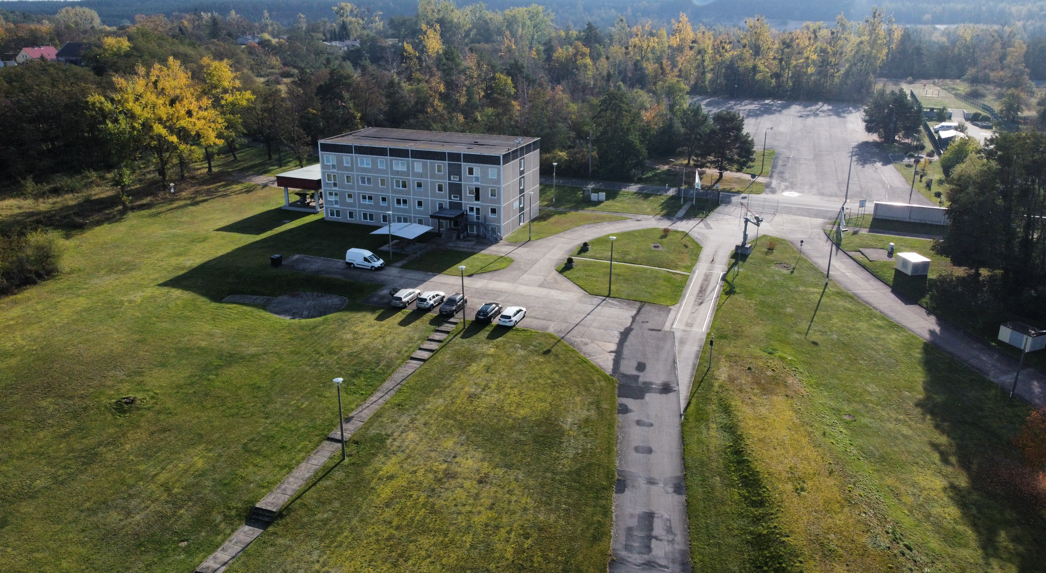 Mehrstöckiges Gebäude mit Zufahrtsstraßen und umliegender Grünfläche.