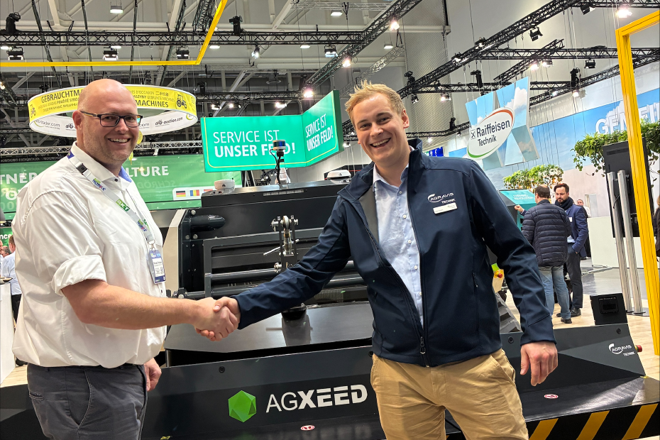 Zwei Personengeben sich vor dem AgXeed-AgBot die Hand; autonome Technik im Fokus