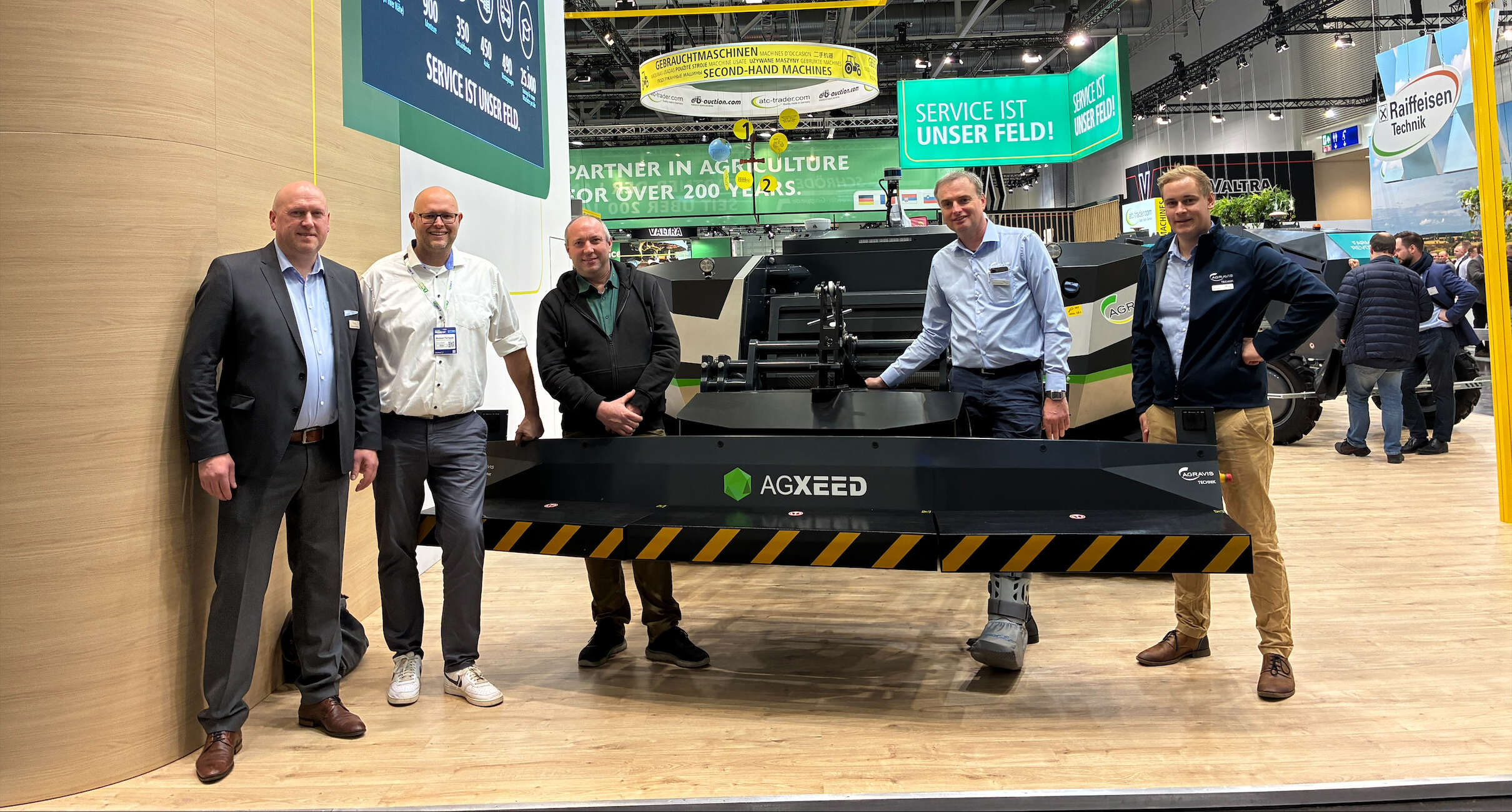 AGRAVIS- und AgXeed-Team präsentiert autonomen AgBot auf Agrarmesse; fünf Personen stehen vor der Ma