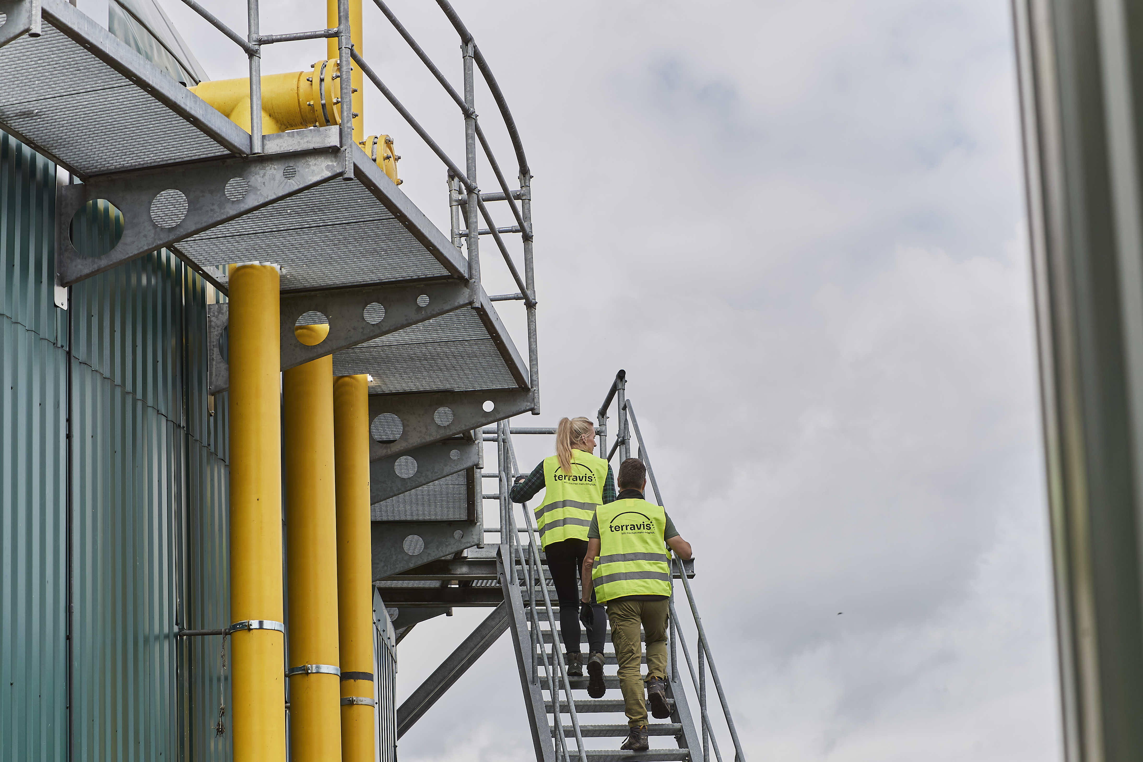 Zwei Personen mit Sicherheitswesten auf einer Biogasanlage