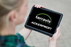 Eine Frau hält ein Tablet. Auf dem Tablet sind das Terravis und Ackerprofi Logo. 