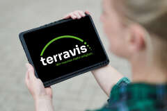 Eine Frau hält ein Tablet. Auf dem Tablet sind das Terravis Logo. 