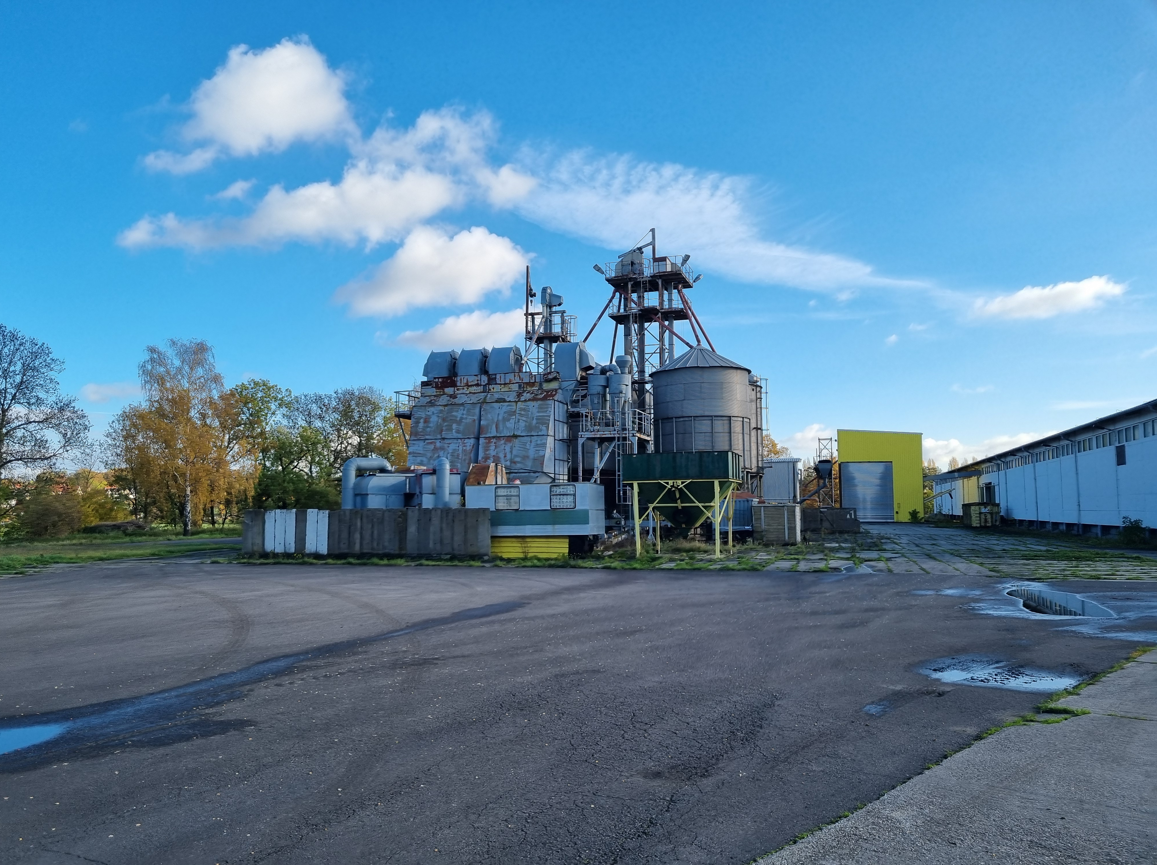 Industrieanlage mit Silos, Rohrleitungen und weitläufiger Asphaltfläche.