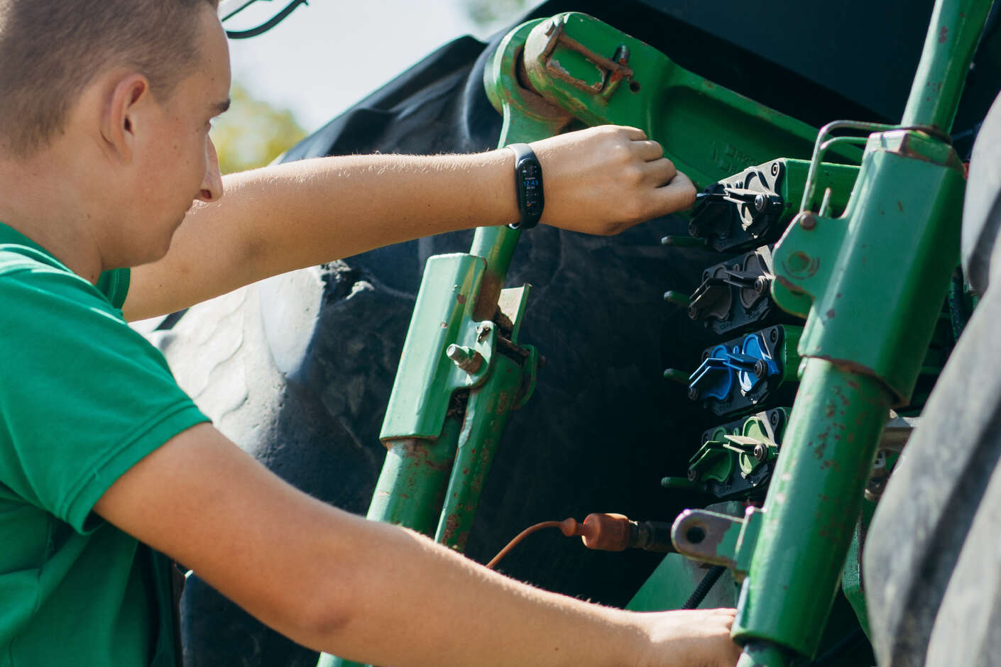 Ein junger Landwirt kontrolliert seinen Traktor. 