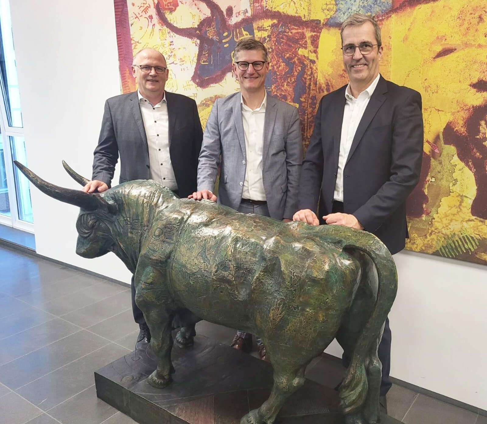 Hermann Hesseler, Tilmann  Fuchs und Dr. Dirk Köckler stehen am AGRAVIS-Stier in der Zentrale. 