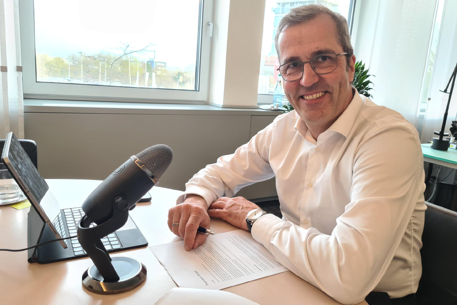 Dr. Dirk Köckler sitz in seinem Büro vor Tablet und Podcast-Mikrofon. 