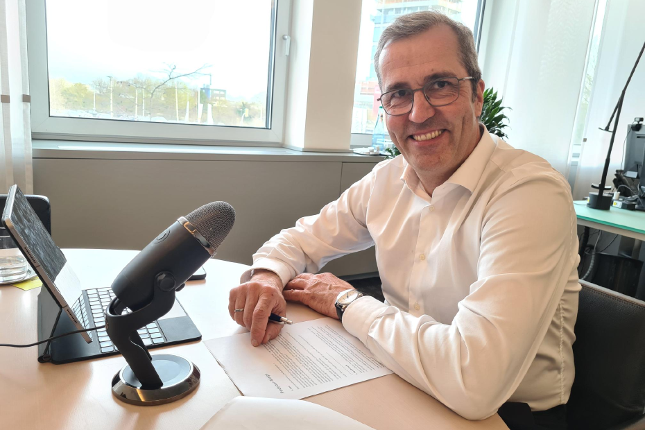 Dr. Dirk Köckler sitz in seinem Büro vor Tablet und Podcast-Mikrofon. 