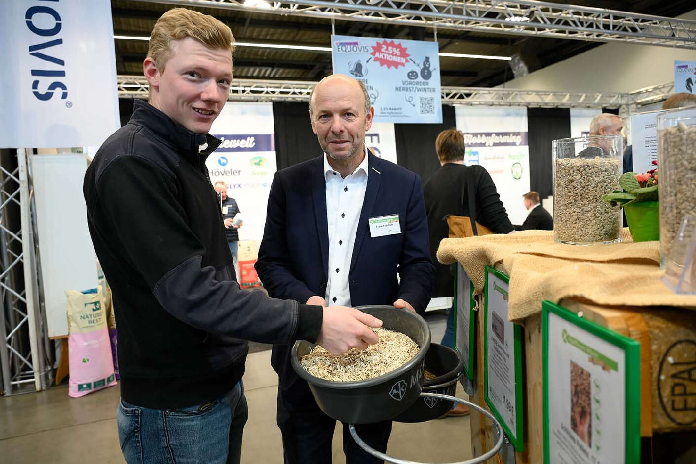 Profi-Springreiter Philipp Schulze Topphoff  und ein AGRAVIS-Berater an einem Messestand mit Pferde-Einstreu