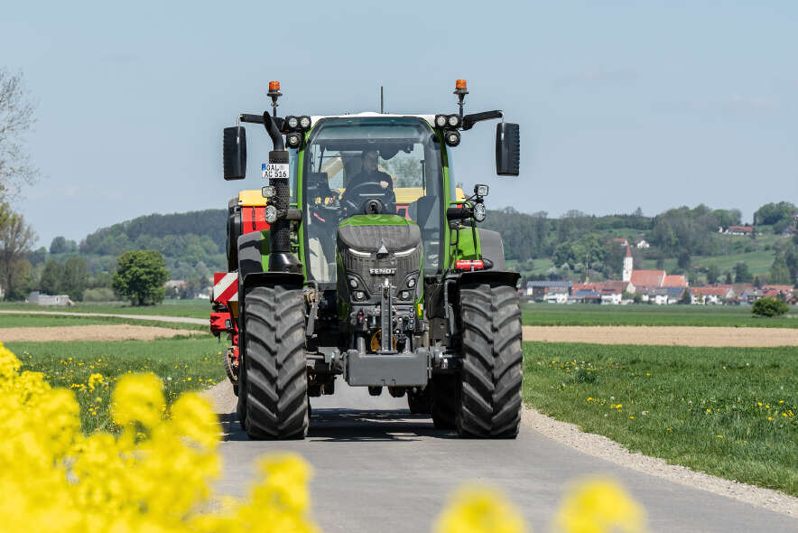 Fendt 500 Vario fährt auf Landstraße durch ländliche Umgebung