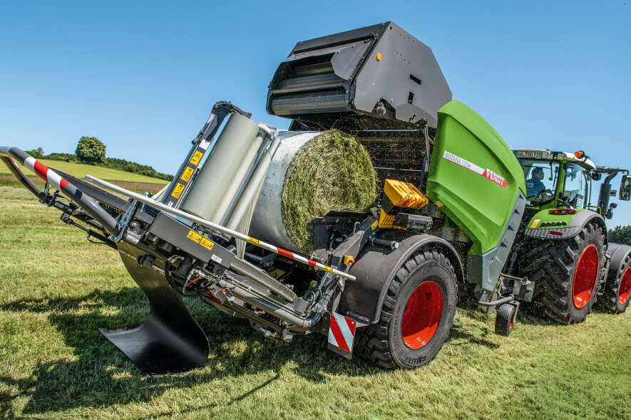 Fendt Rotana Rundballenpresse mit gewickeltem Silageballen während der Heuernte auf dem Feld.