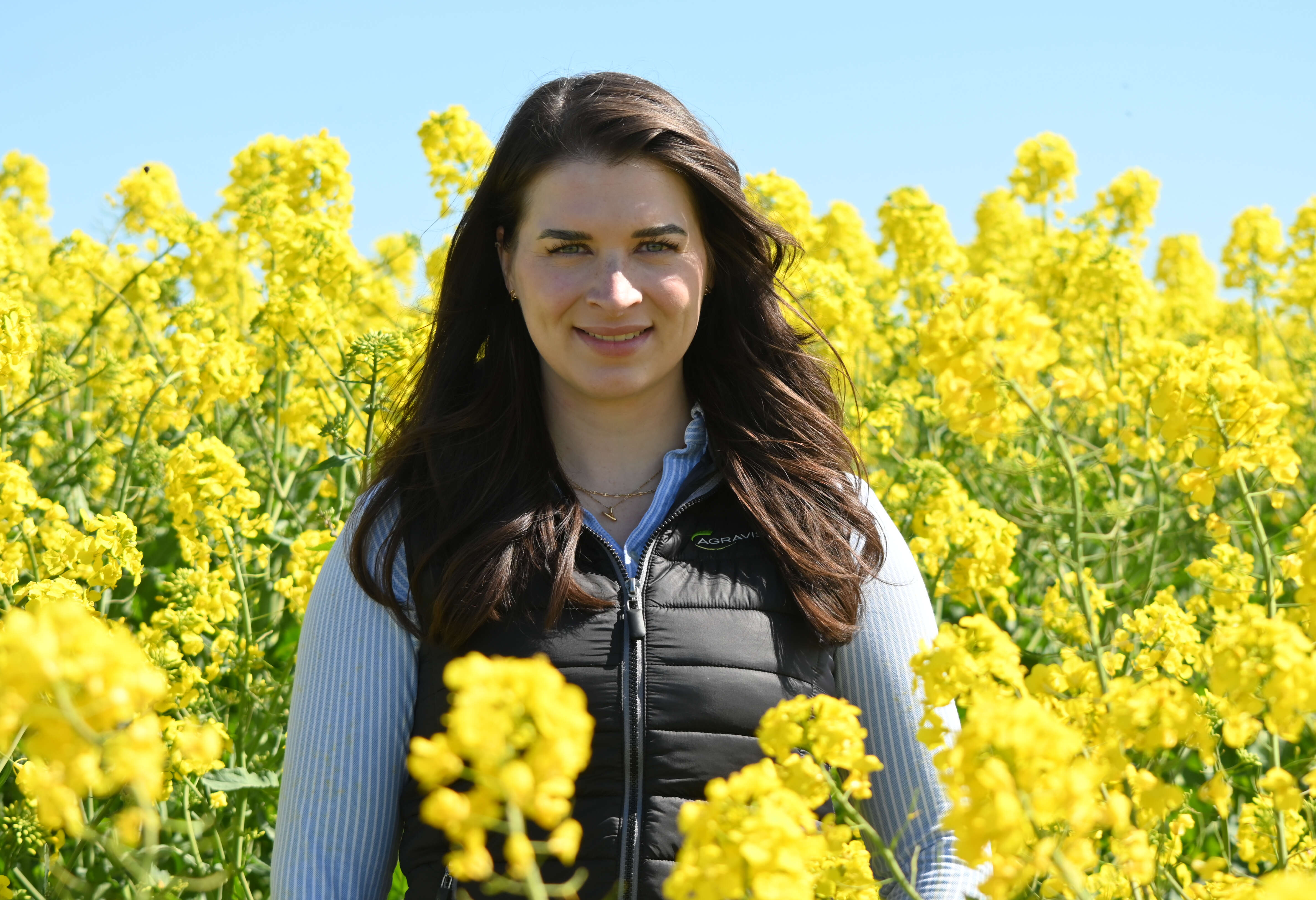 AGRAVIS-Expertin Anastasia Thiem steht in einem Rapsfeld mit gelben Blüten.