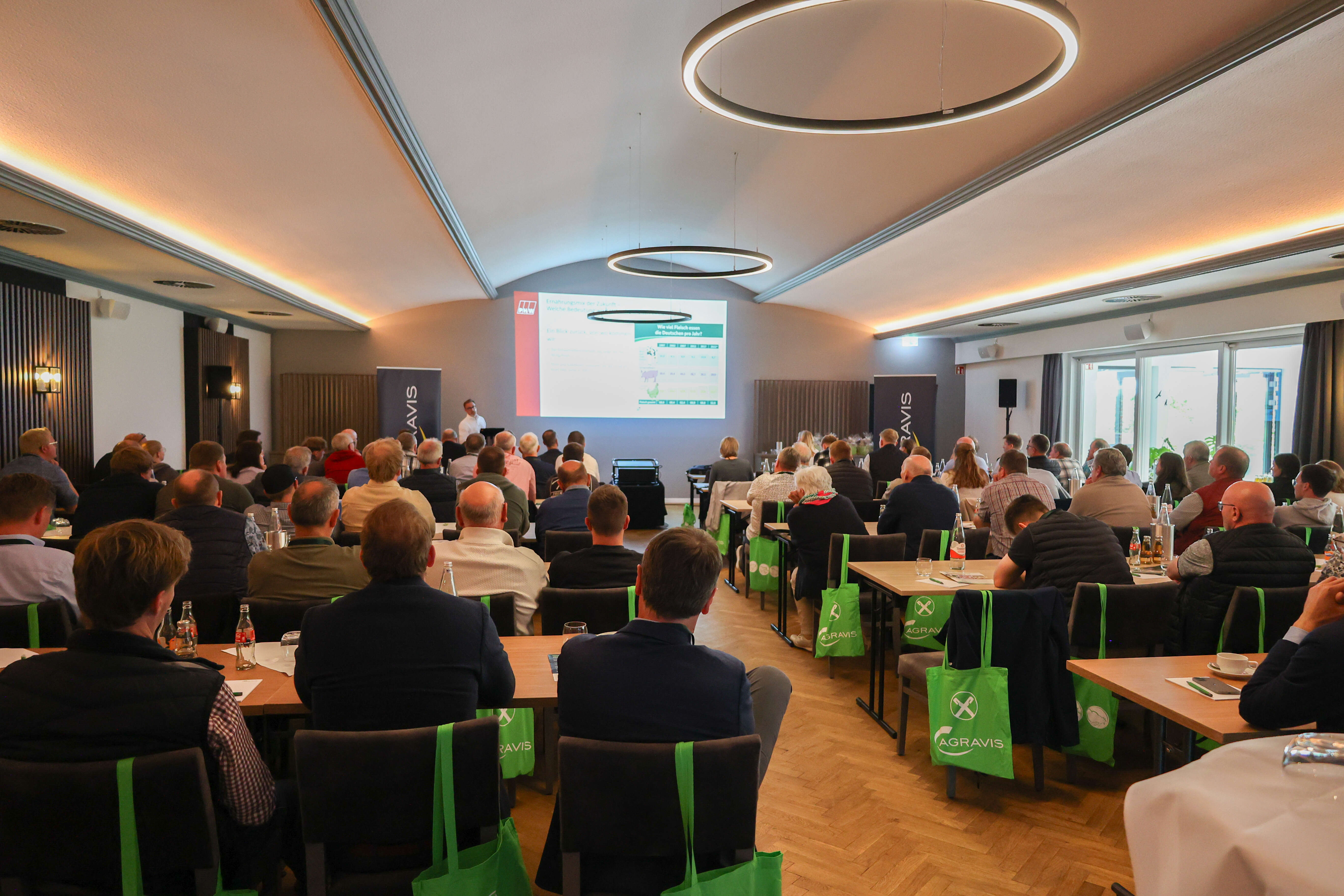 Viele Personen sitzen in einem Raum und hören einem Vortrag zu
