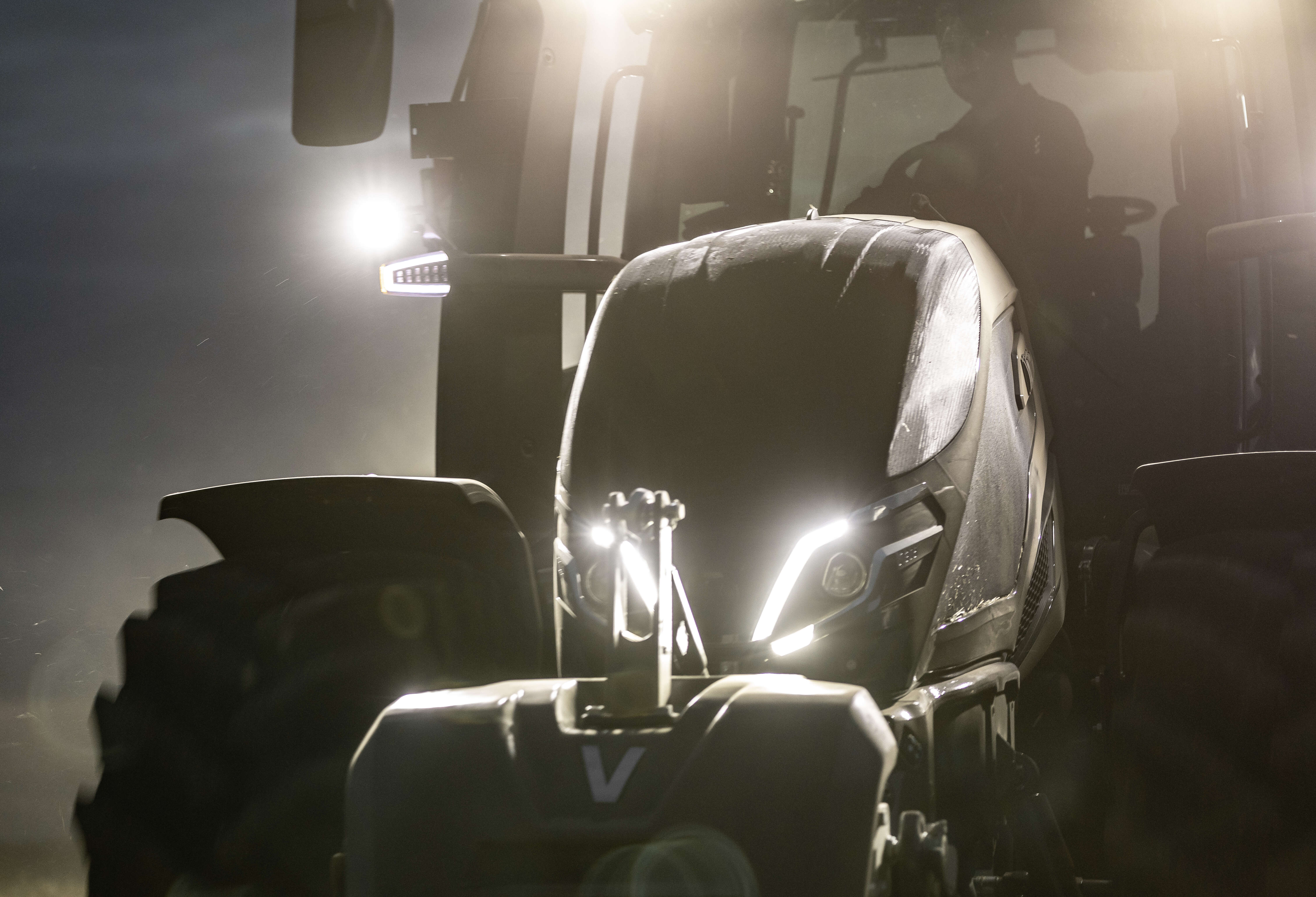 Valtra Traktor Frontansicht bei Dämmerung mit eingeschalteten LED-Scheinwerfern im Feldeinsatz