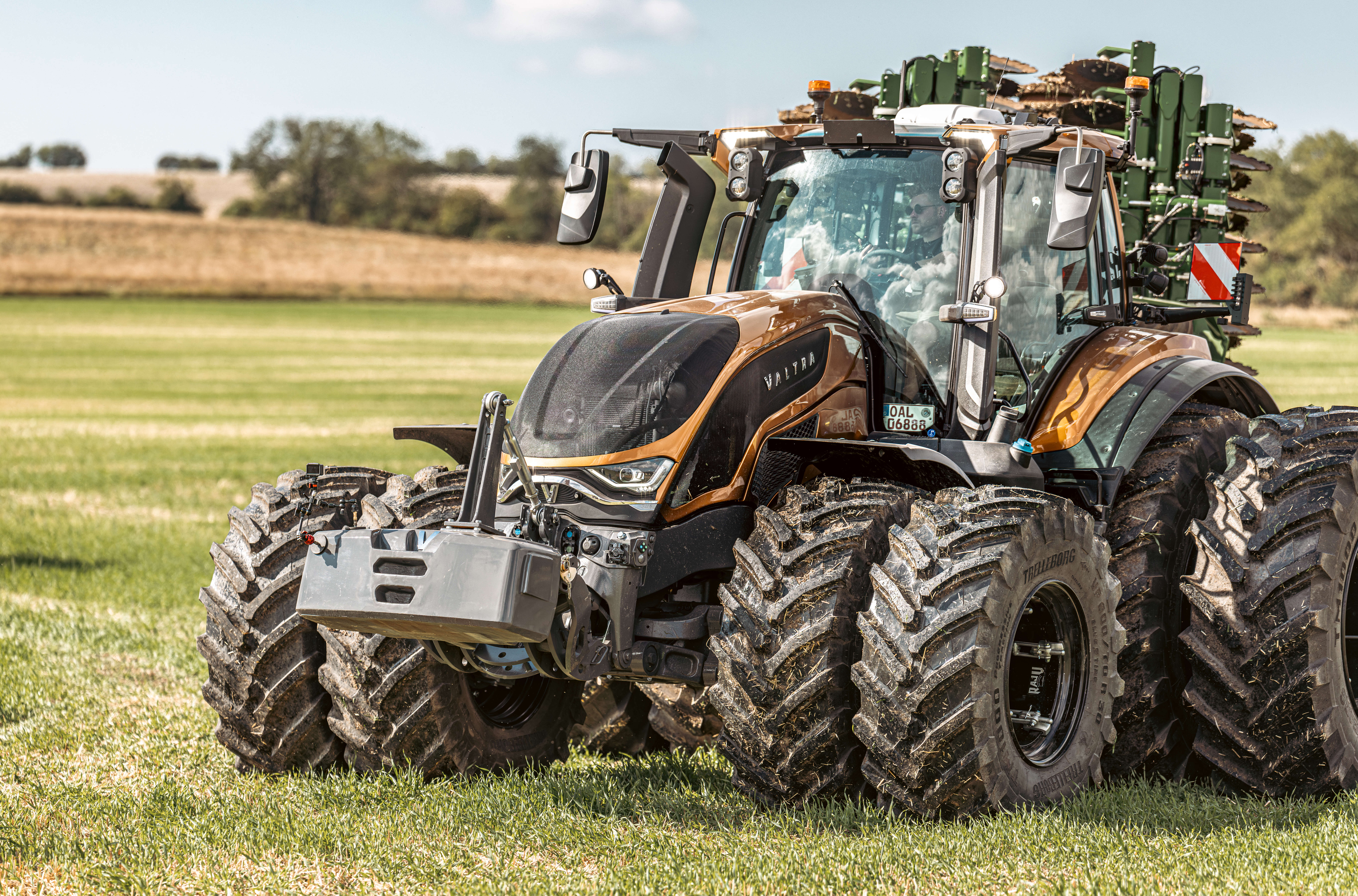 Valtra Traktor Frontansicht bei Dämmerung mit eingeschalteten LED-Scheinwerfern im Feldeinsatz