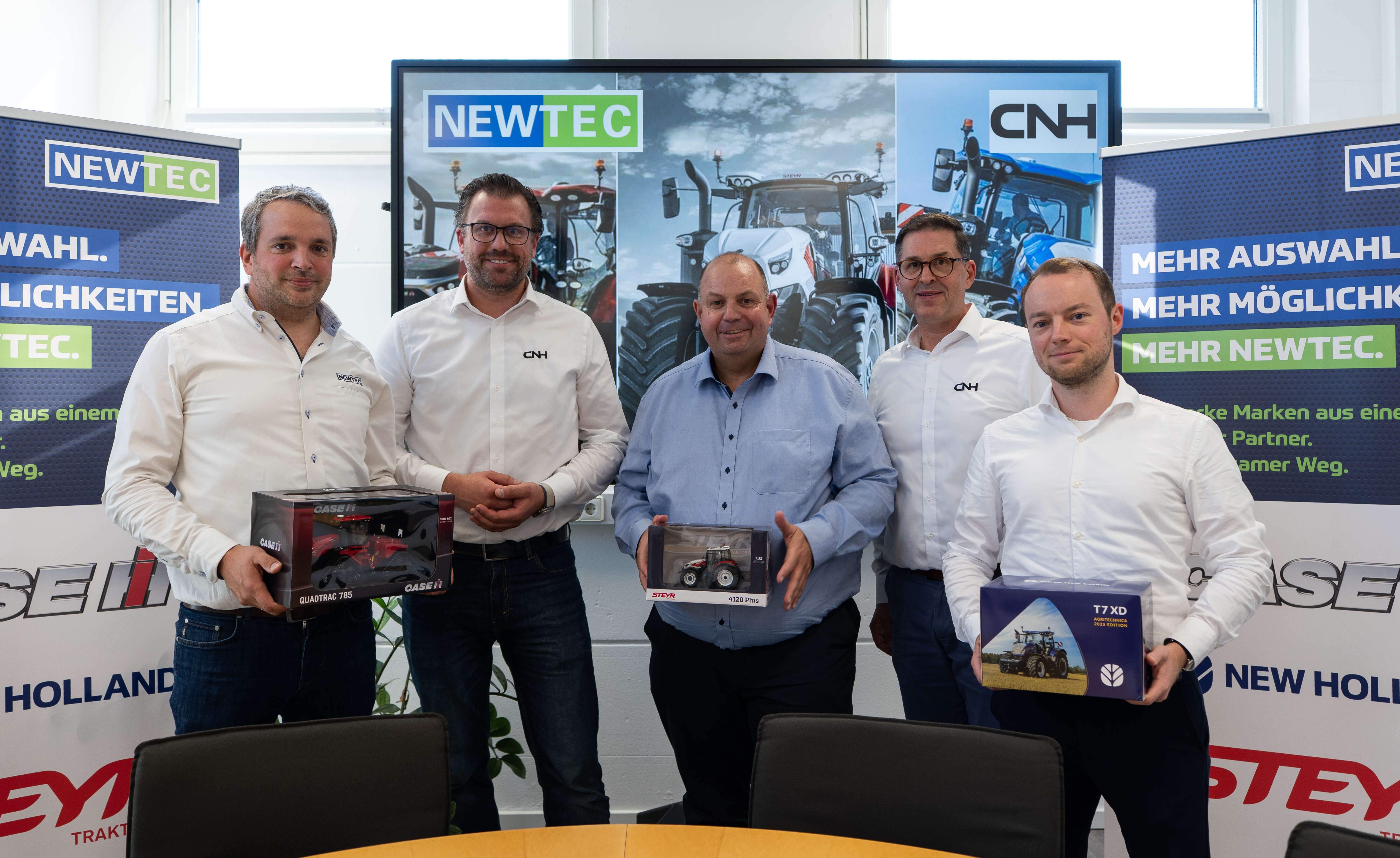 Fünf Männer stehen vor Aufstellern mit der Beschriftun Newtec und CNH