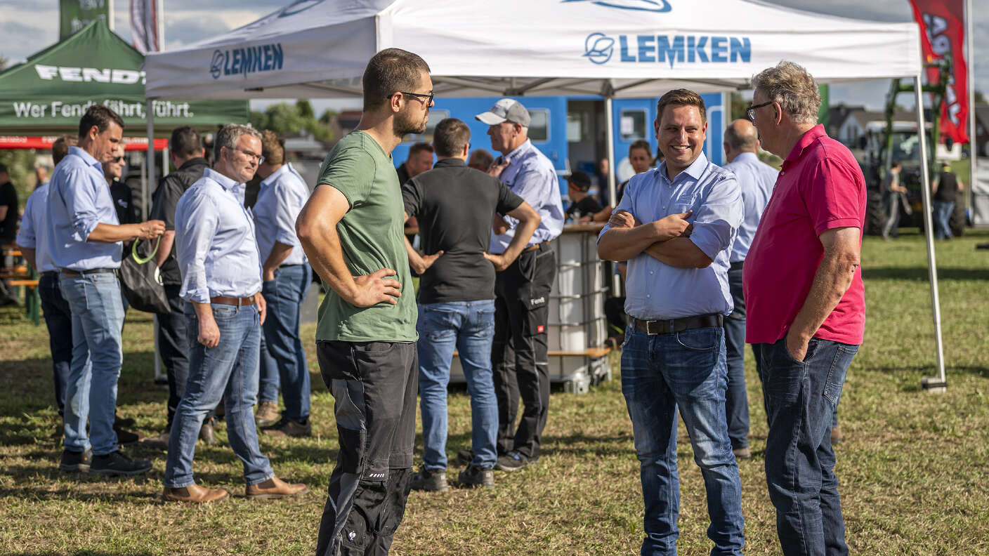 Besucher im Gespräch vor einem LEMKEN Pavillon auf einer Landtechnikveranstaltung.