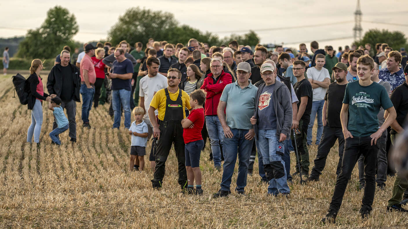 Besucher auf einem Stoppelfeld verfolgen eine Landtechnik-Vorführung.