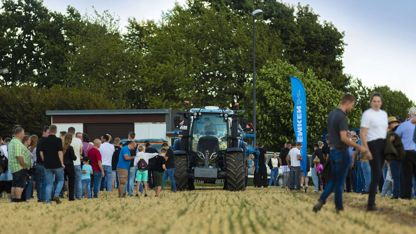 Fendt Traktor vor Besuchern auf einer Landtechnikveranstaltung im Stoppelfeld.