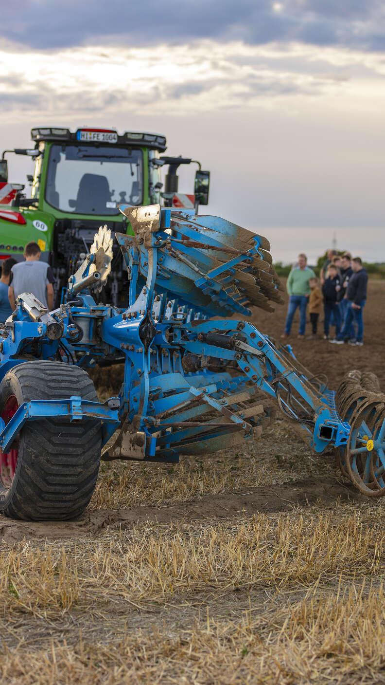 Fendt Traktor mit LEMKEN Sämaschine auf einem Vorführfeld, Besucher im Hintergrund.