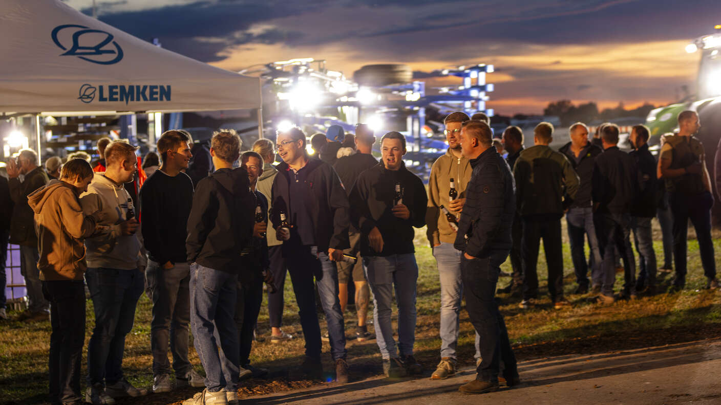 Besuchergruppen vor einem LEMKEN Pavillon auf einer Landtechnikveranstaltung bei Abenddämmerung.