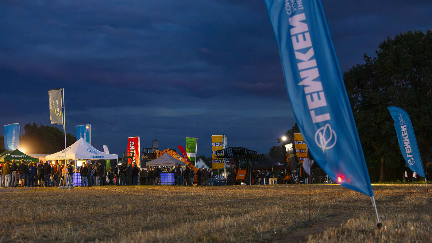 LEMKEN Fahnen und Veranstaltungszelte auf einem Stoppelfeld bei Abenddämmerung.
