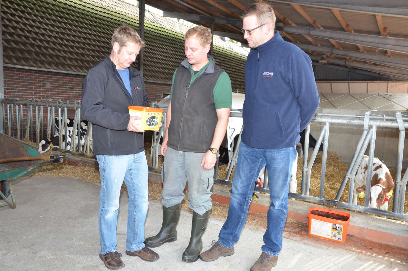 Lutz Tönjes, Gerald Krabbe und Arndt Griepenkerl stehen mit einem Kübel Crystalyx im Stall.