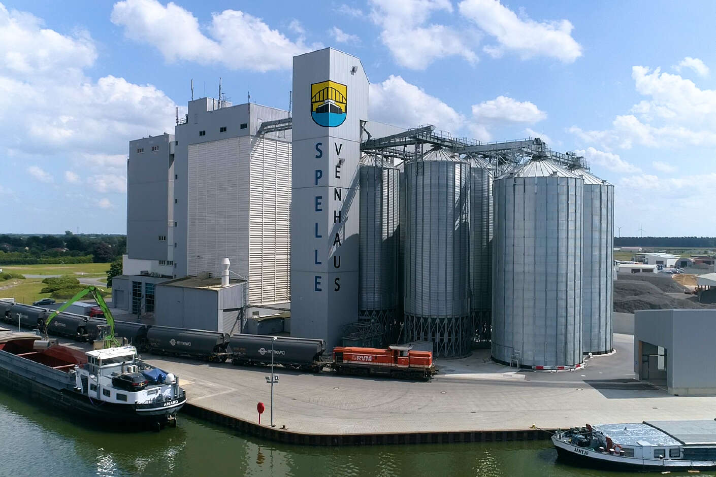 Mühlengebäude mit mehren Rundsilos am Wasser gelegen. Im Wasser schwimmen zwei Schiffe